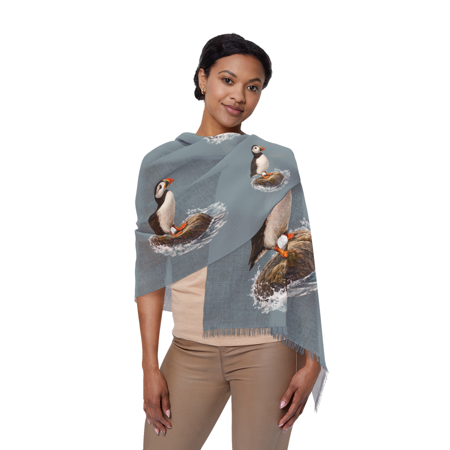 Woman wearing the Bram slate blue wrap scarf printed with puffins on coastal rocks